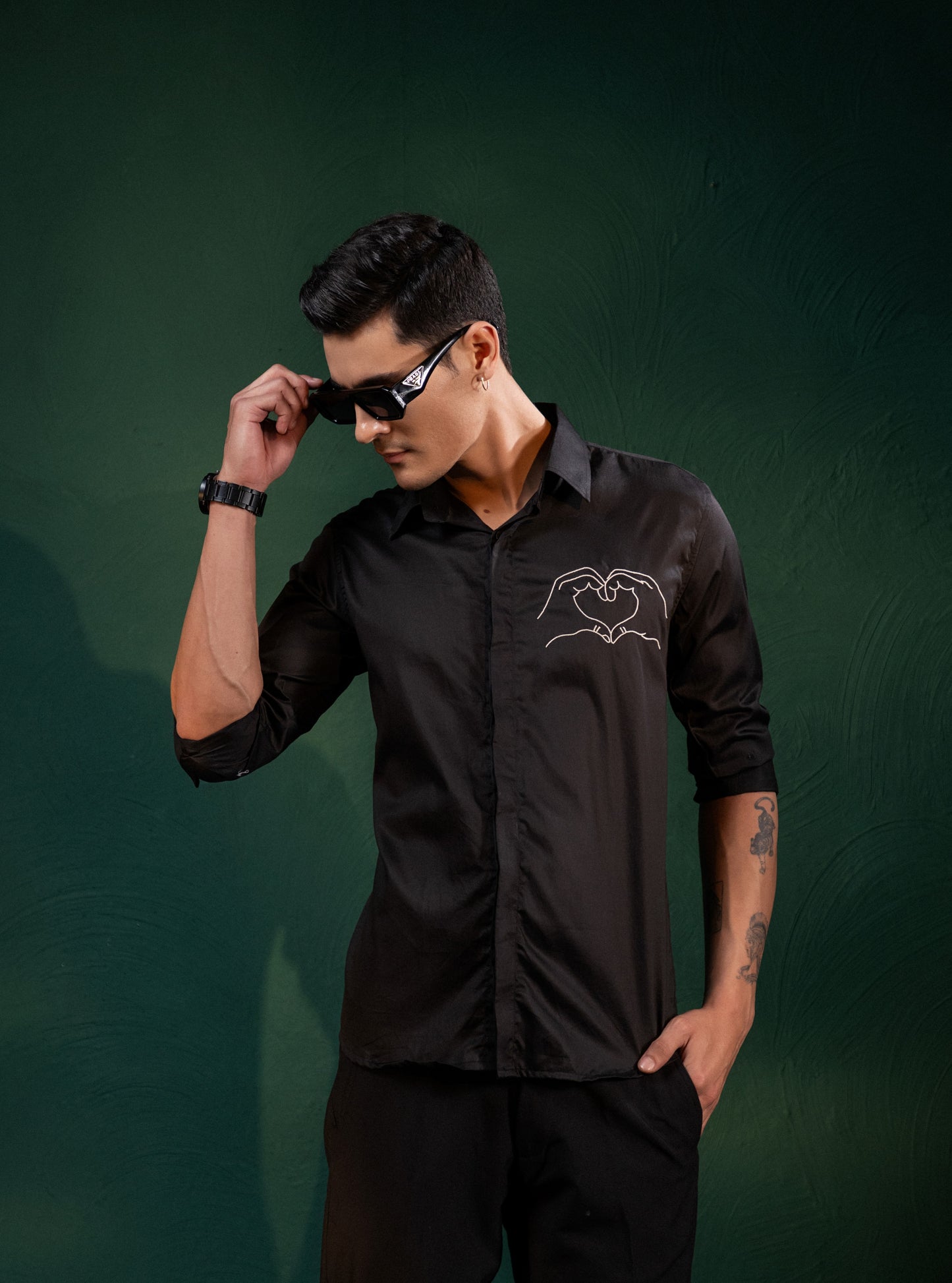 A HEART GESTURE SHOWN WITH HANDS EMBROIDERED ON A SHIRT