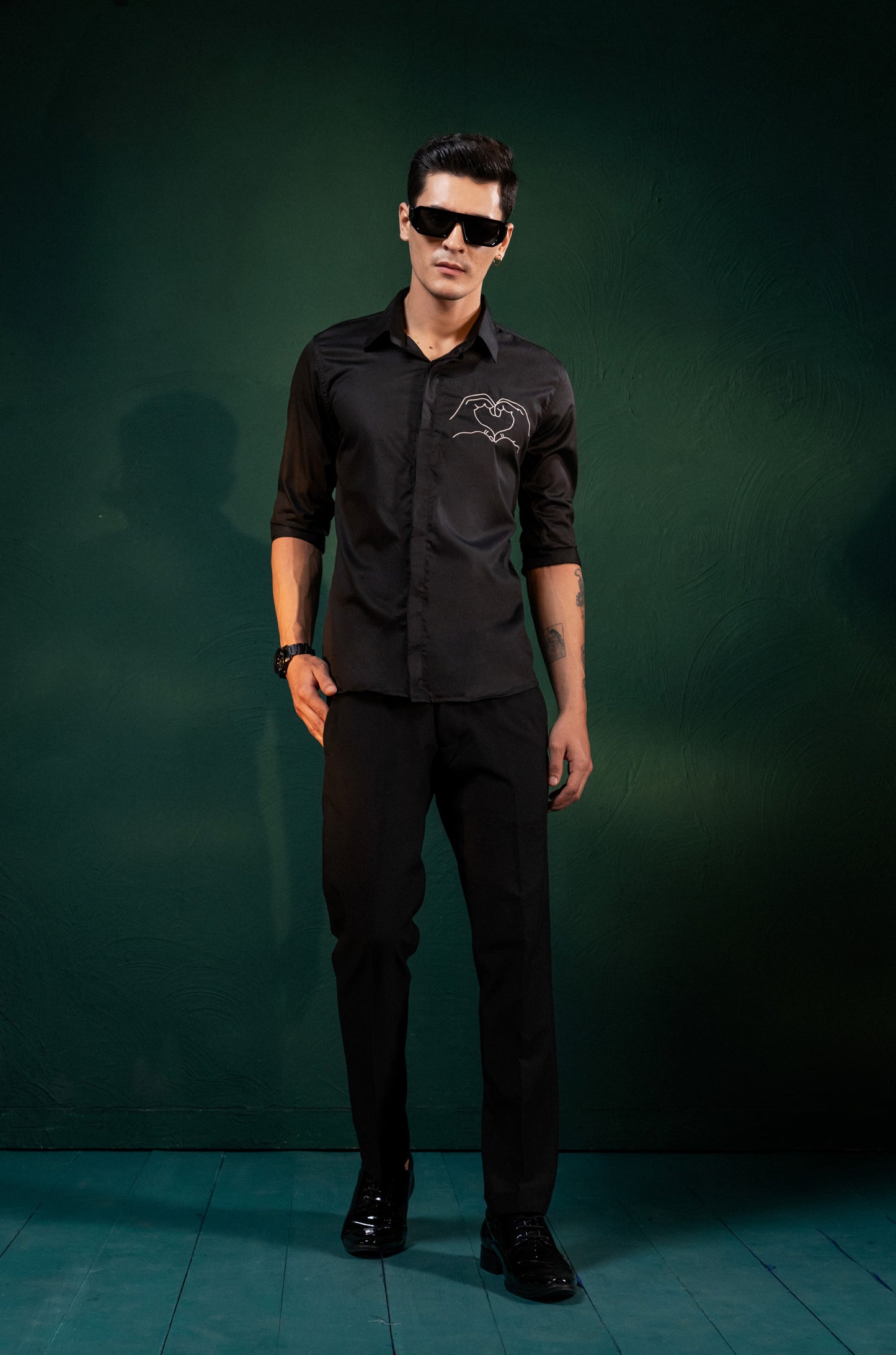 A HEART GESTURE SHOWN WITH HANDS EMBROIDERED ON A SHIRT