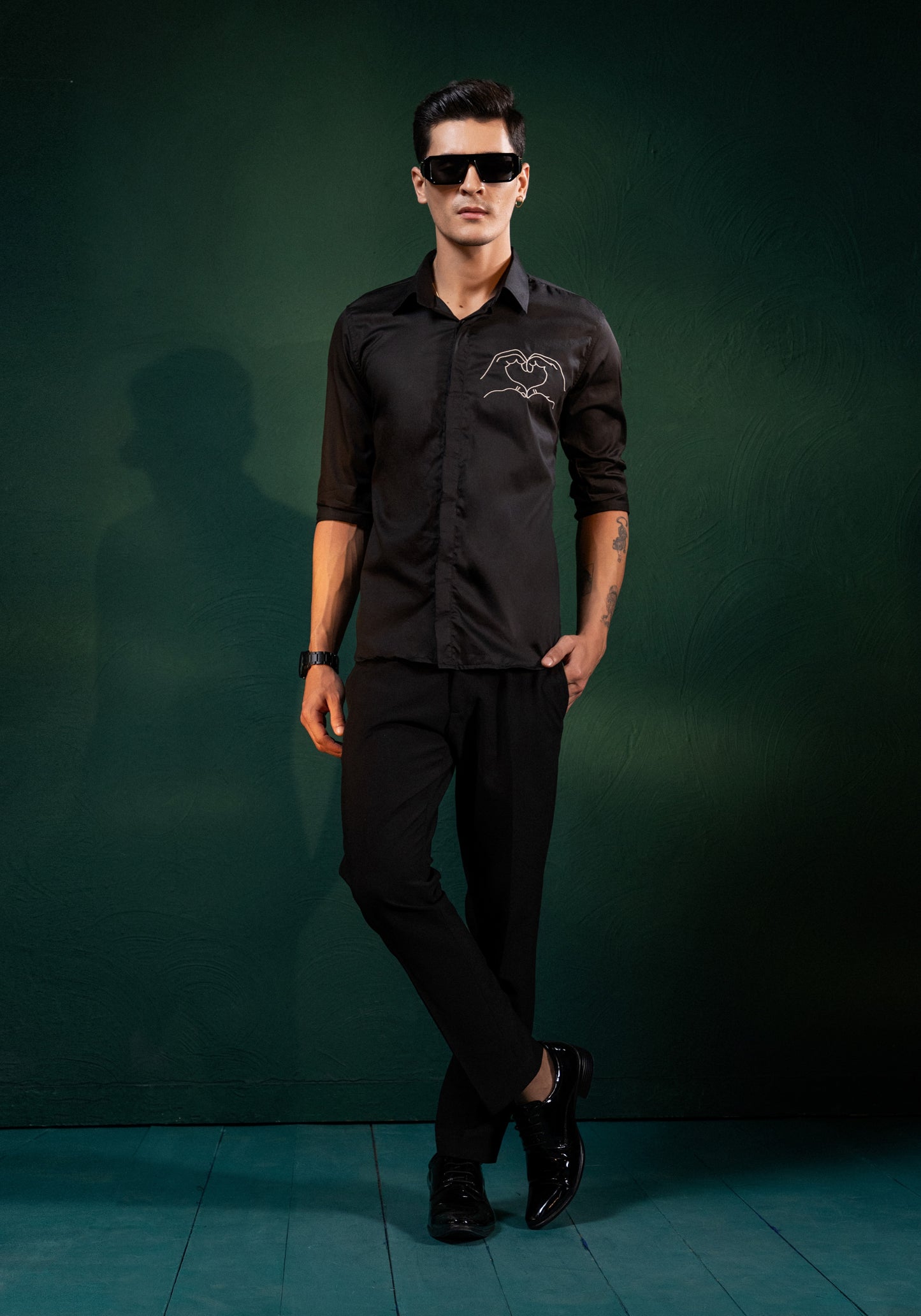 A HEART GESTURE SHOWN WITH HANDS EMBROIDERED ON A SHIRT