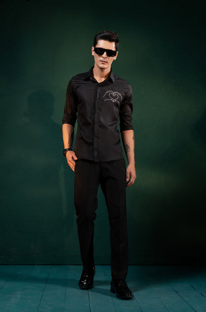 A HEART GESTURE SHOWN WITH HANDS EMBROIDERED ON A SHIRT